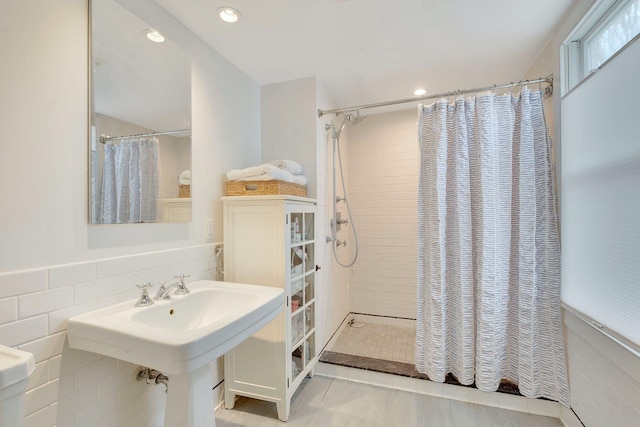 bathroom with a sink, tile walls, and tiled shower