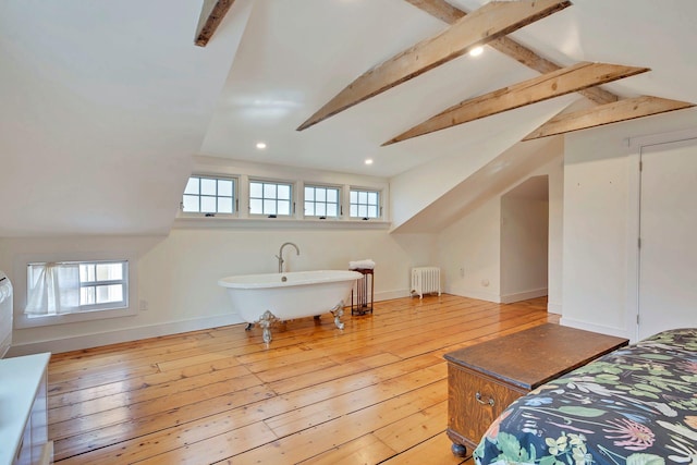 bedroom featuring radiator heating unit, baseboards, light wood-type flooring, and vaulted ceiling with beams