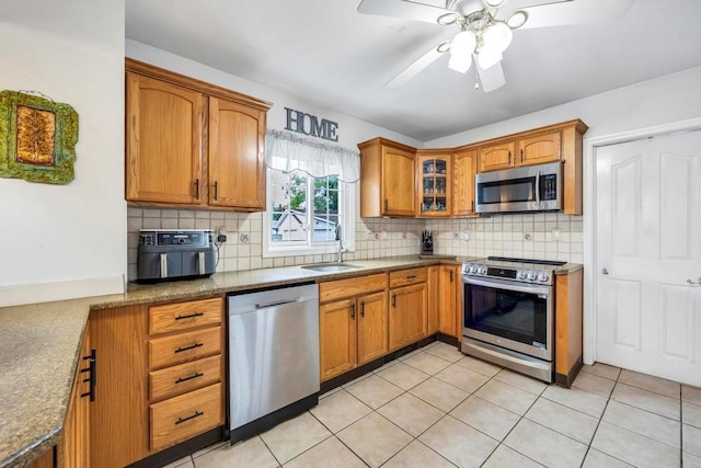 kitchen with backsplash, ceiling fan, appliances with stainless steel finishes, light tile patterned flooring, and light stone counters