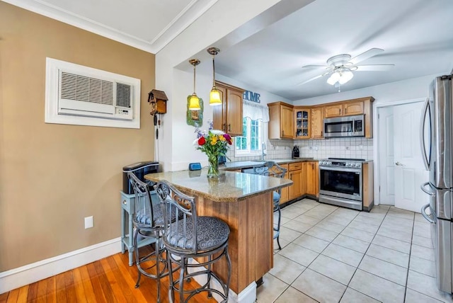 kitchen featuring kitchen peninsula, a kitchen breakfast bar, dark stone counters, stainless steel appliances, and decorative light fixtures