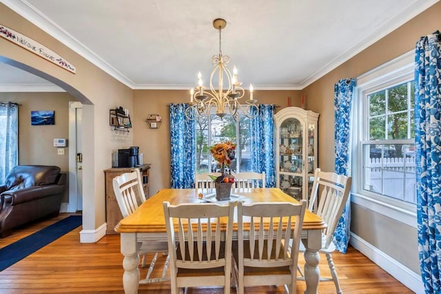 dining area with light wood-type flooring, an inviting chandelier, and ornamental molding