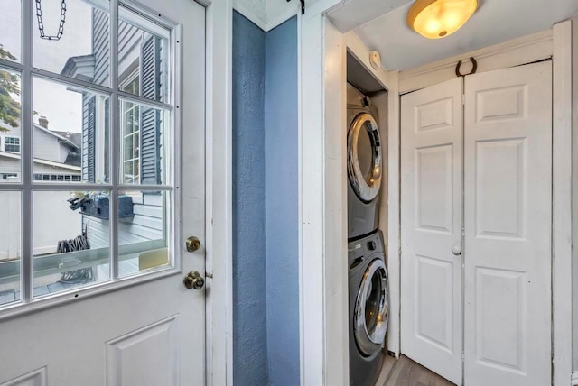 clothes washing area with hardwood / wood-style flooring, a barn door, and stacked washer and dryer