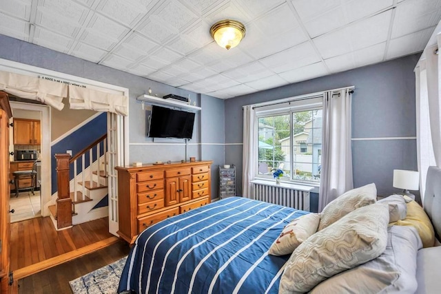 bedroom with dark hardwood / wood-style flooring and radiator heating unit