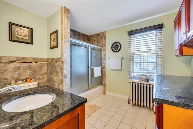 bathroom with tile patterned floors, radiator, vanity, and bath / shower combo with glass door