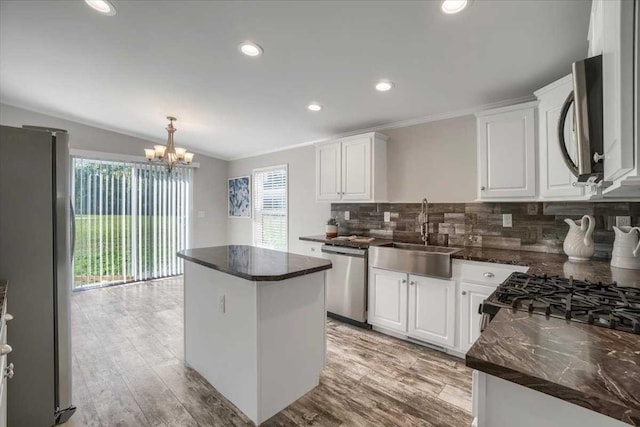 kitchen featuring appliances with stainless steel finishes, a center island, white cabinetry, and sink