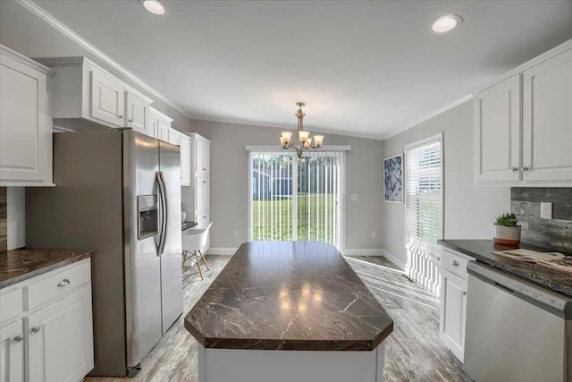 kitchen with backsplash, vaulted ceiling, appliances with stainless steel finishes, a kitchen island, and a chandelier