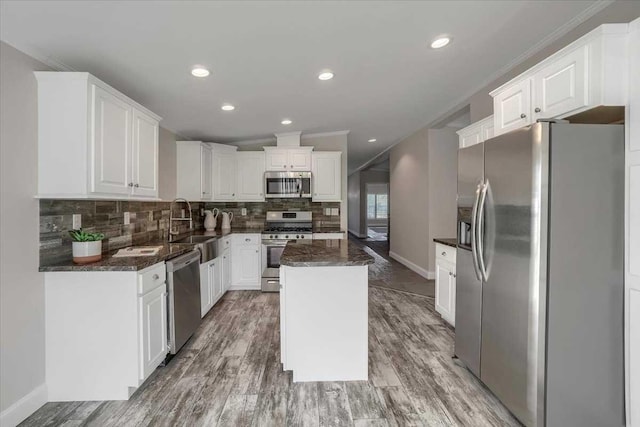 kitchen with hardwood / wood-style flooring, a center island, white cabinetry, and stainless steel appliances