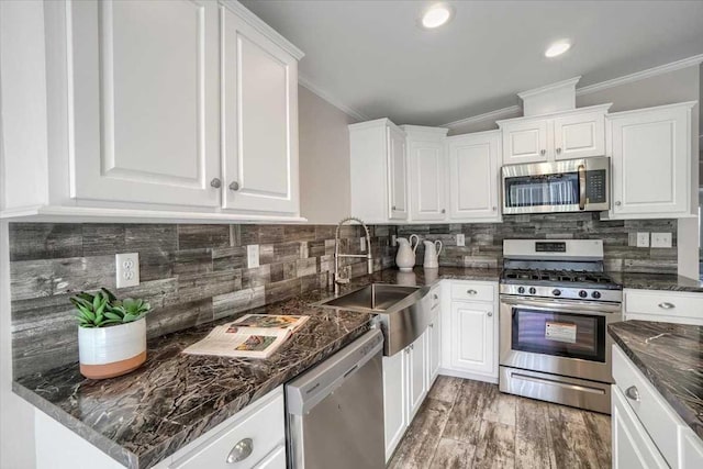 kitchen featuring sink, white cabinets, ornamental molding, and appliances with stainless steel finishes