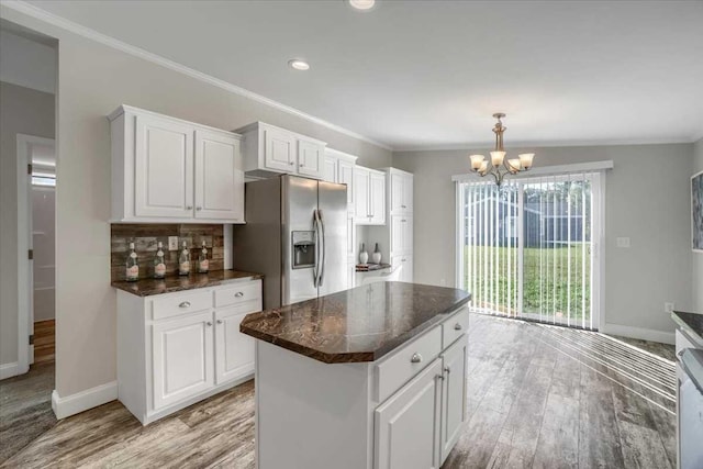 kitchen with stainless steel fridge, a kitchen island, white cabinetry, and tasteful backsplash