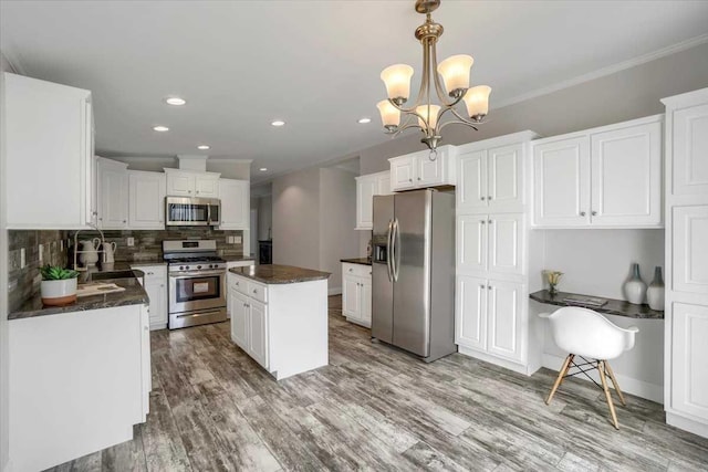 kitchen with appliances with stainless steel finishes, backsplash, decorative light fixtures, a center island, and white cabinetry