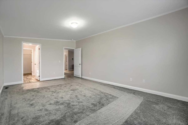 unfurnished bedroom with a walk in closet, carpet floors, and ornamental molding