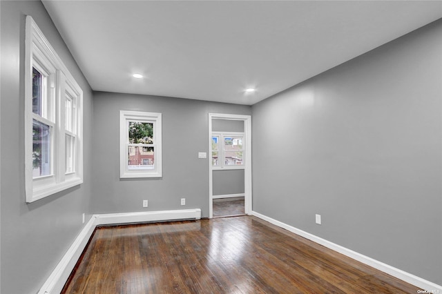 spare room featuring baseboard heating and dark wood-type flooring