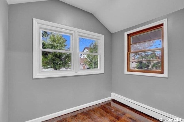 unfurnished room with hardwood / wood-style floors, a baseboard radiator, and lofted ceiling