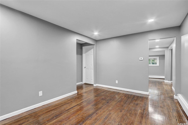 spare room with baseboard heating and dark wood-type flooring