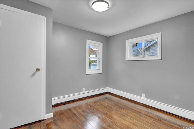 unfurnished room featuring hardwood / wood-style floors and a baseboard heating unit