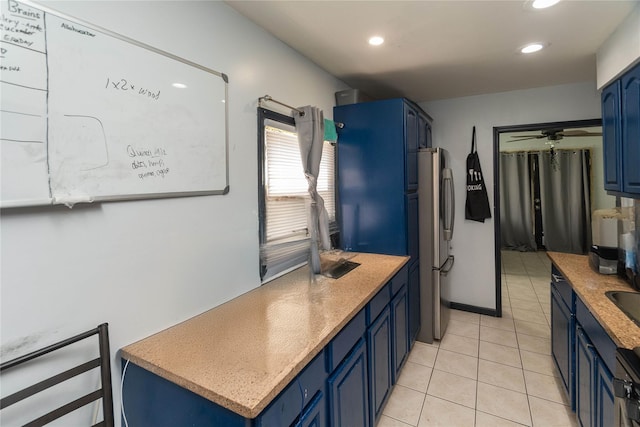 kitchen with ceiling fan, stainless steel fridge, blue cabinets, and light tile patterned floors