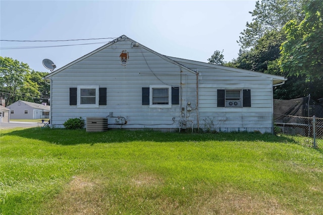 back of house featuring central AC unit and a lawn