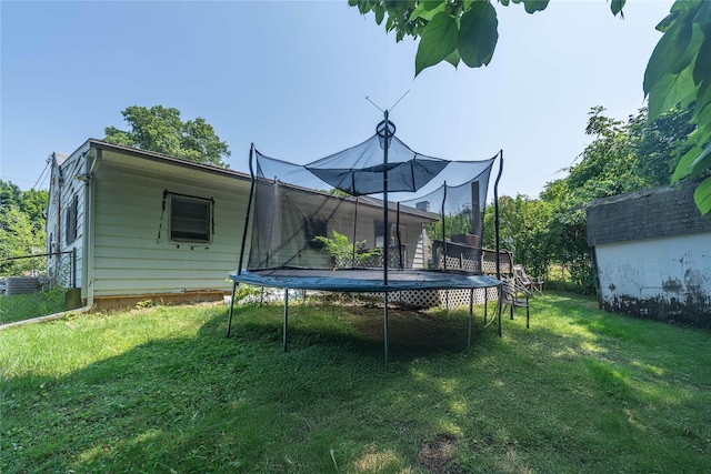 back of property featuring a storage unit, a trampoline, and a yard