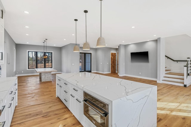 kitchen featuring a large island, decorative light fixtures, white cabinetry, and light wood-type flooring