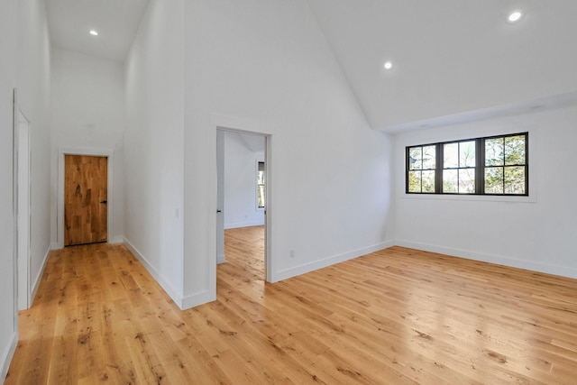 empty room featuring light wood-type flooring and high vaulted ceiling