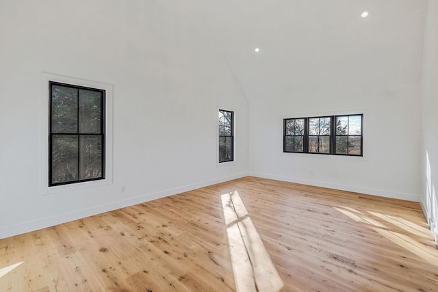 empty room with light hardwood / wood-style floors and high vaulted ceiling