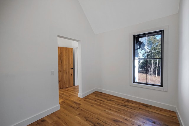 unfurnished room featuring plenty of natural light, wood-type flooring, and vaulted ceiling