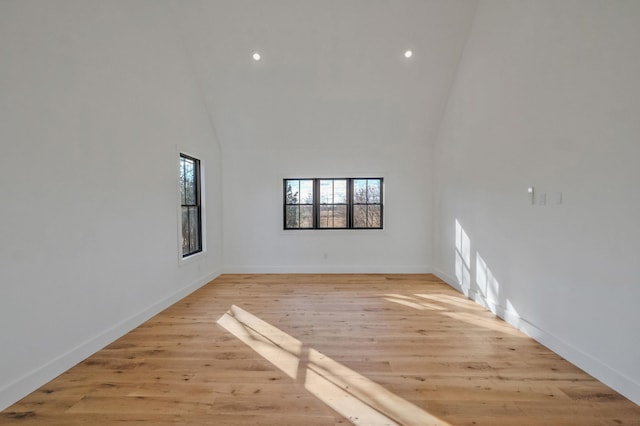 spare room featuring high vaulted ceiling and light wood-type flooring