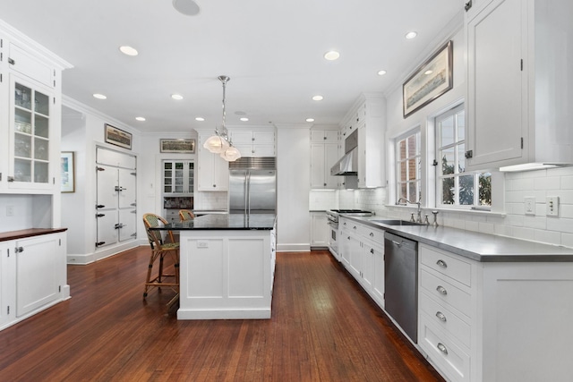 kitchen featuring stainless steel appliances, a center island, pendant lighting, white cabinets, and sink