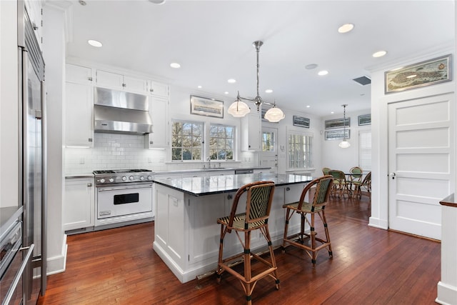 kitchen featuring white cabinetry, a kitchen bar, stainless steel range, hanging light fixtures, and a center island