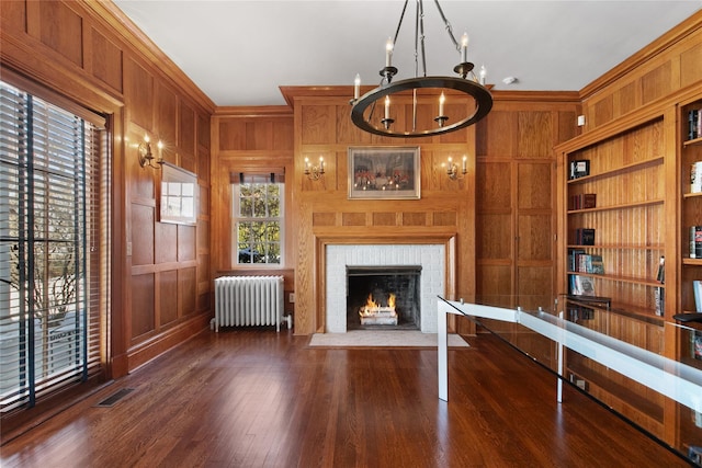 36 Revolutionary Rd, Briarcliff Manor, NY 10510 - unfurnished living room featuring radiator, wood walls, a chandelier, built in features, and a brick fireplace