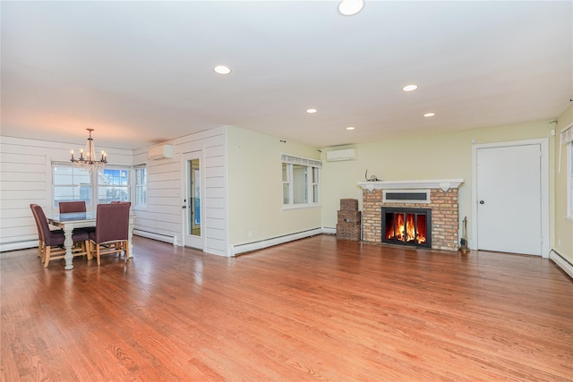 living room featuring hardwood / wood-style floors, an AC wall unit, a brick fireplace, and a baseboard radiator