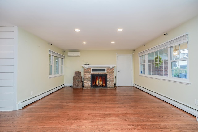 unfurnished living room with a wall mounted air conditioner, wood-type flooring, and a baseboard radiator