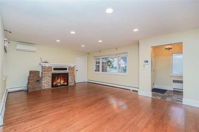 unfurnished living room featuring radiator, a wall unit AC, baseboard heating, wood-type flooring, and a fireplace