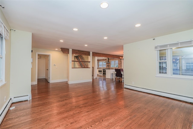 unfurnished living room featuring wood-type flooring, a notable chandelier, and a baseboard heating unit