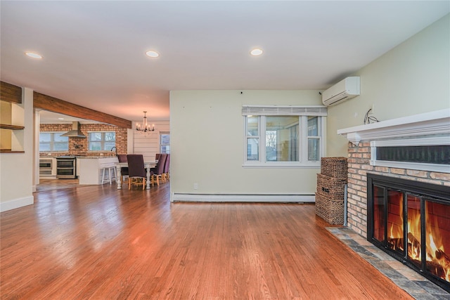 living room featuring a wall unit AC, a brick fireplace, wood-type flooring, and baseboard heating