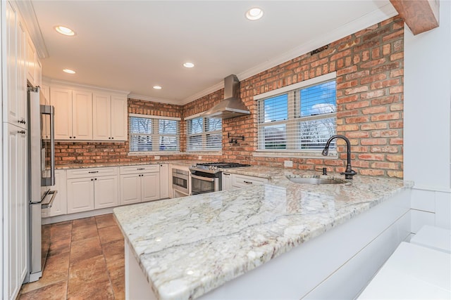 kitchen featuring kitchen peninsula, stainless steel appliances, white cabinetry, and wall chimney exhaust hood