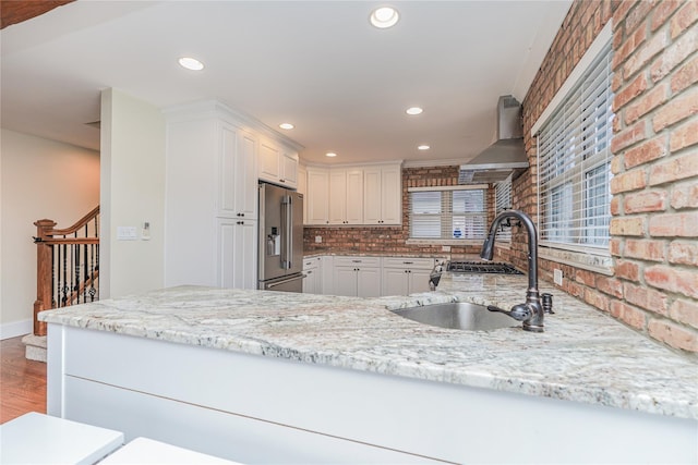 kitchen featuring white cabinets, high end fridge, wall chimney exhaust hood, and hardwood / wood-style floors