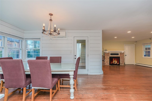 dining room featuring hardwood / wood-style flooring, an inviting chandelier, a fireplace, and a baseboard radiator