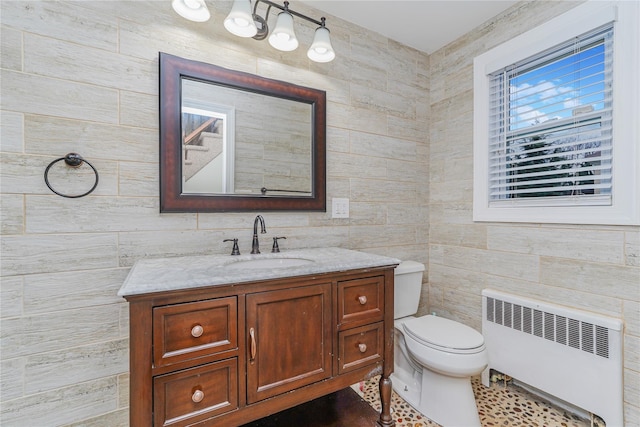 bathroom featuring vanity, toilet, tile walls, and radiator