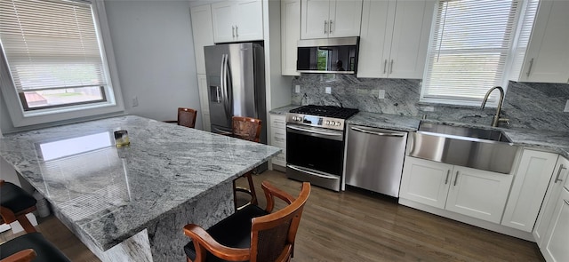 kitchen with light stone countertops, appliances with stainless steel finishes, white cabinetry, and sink