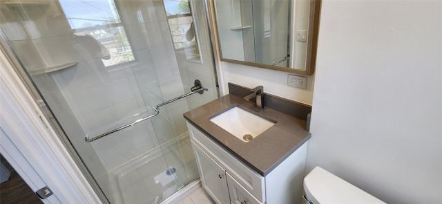 bathroom with vanity, toilet, and a shower with door