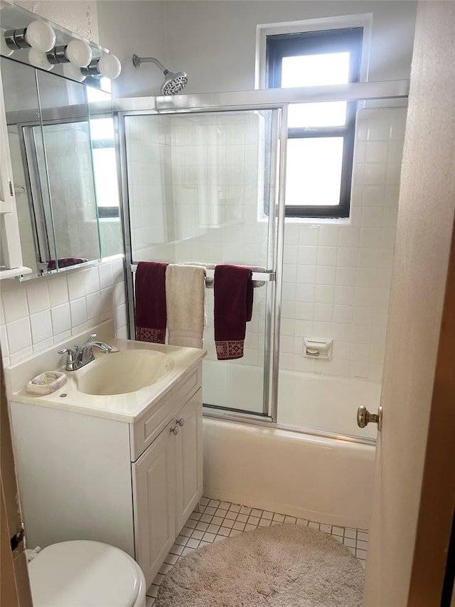 full bathroom with vanity, bath / shower combo with glass door, tile patterned flooring, toilet, and tasteful backsplash