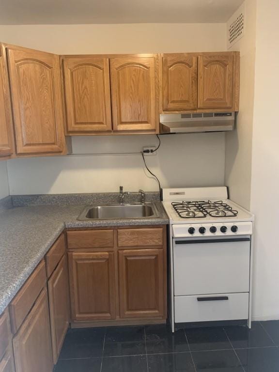 kitchen featuring white range, dark tile patterned floors, and sink