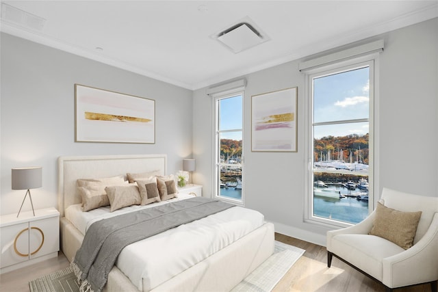 bedroom featuring ornamental molding, wood-type flooring, and a water view