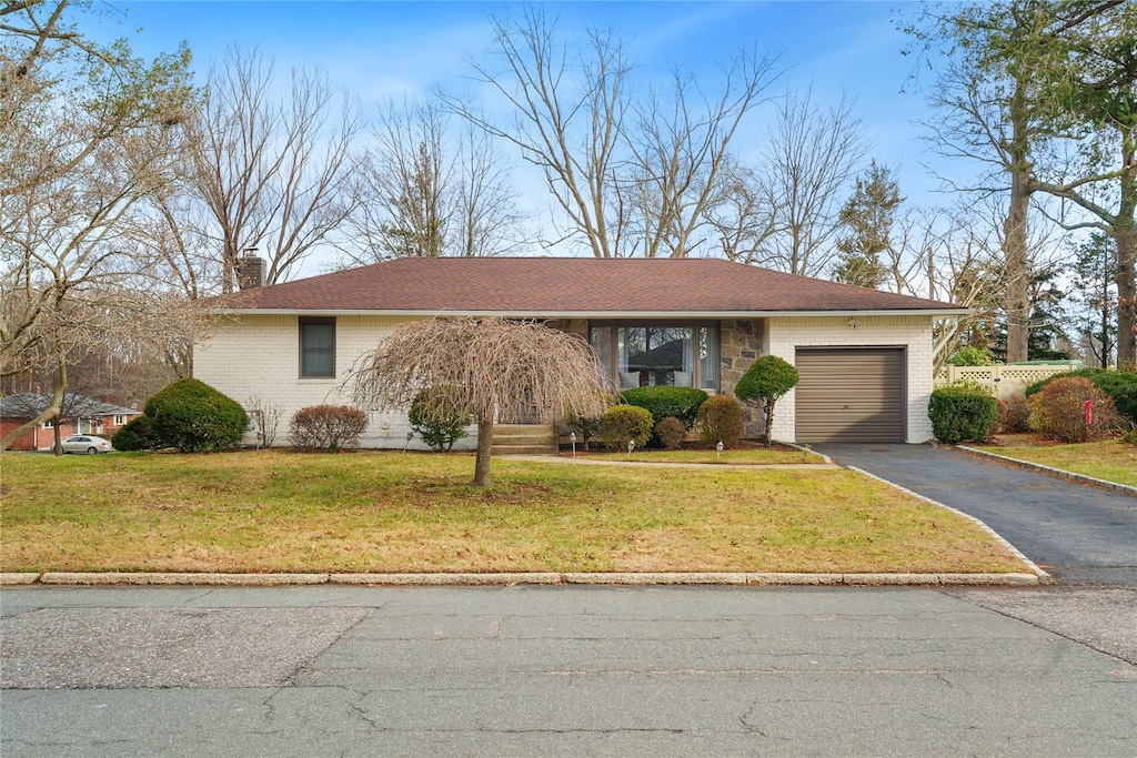 ranch-style house featuring a garage and a front lawn