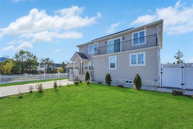 rear view of house with a lawn and a balcony