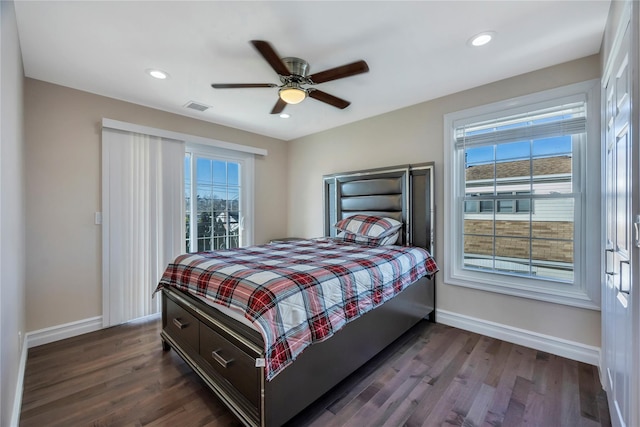 bedroom featuring dark hardwood / wood-style floors, ceiling fan, and multiple windows