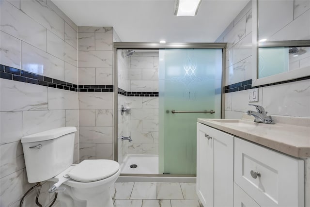 bathroom featuring vanity, toilet, a shower with shower door, and tile walls