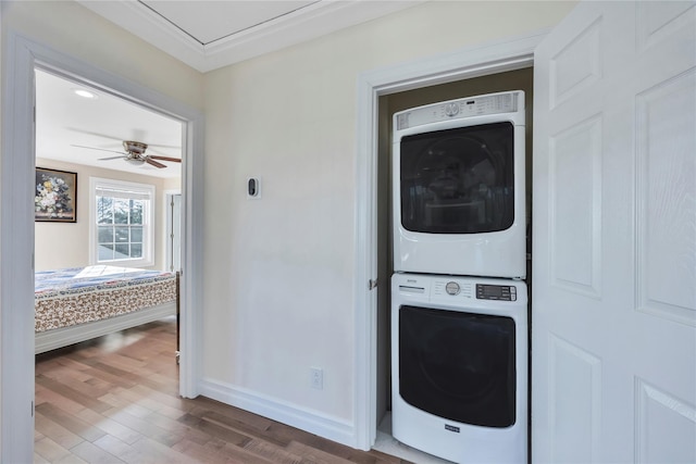 clothes washing area with stacked washer and dryer, hardwood / wood-style flooring, ornamental molding, and ceiling fan