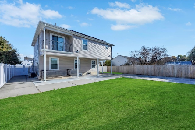 rear view of house featuring a balcony, a yard, and a patio